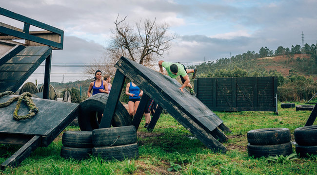 Group of participants in an obstacle course climbing an inverted wall