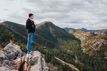Fototapeta premium Young male enjoys mountains and nature. Nice landscape scenery. Highway with cars in background.