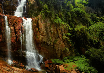 Travel destination Ramboda Falls, 109m in high waterfalls, flowing over red rocks  surrounded by tropical forest. Hill Country, Nuwara Eliya, Ramboda of Pussallawa, Sri Lanka.