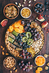 Middle East sweets, dry fruits and nuts on a copper tray. Top view, wooden background