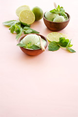 Lime ice cream with mint. Ice cream in wooden bowls on a light pink background