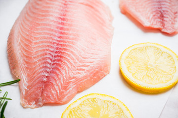 Raw tilapia fish fillet on the cutting board. Selective focus. Shallow depth of field.