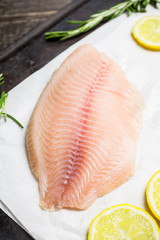 Raw tilapia fish fillet on the cutting board. Selective focus. Shallow depth of field.