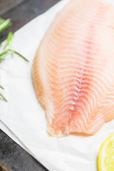 Raw tilapia fish fillet on the cutting board. Selective focus. Shallow depth of field.