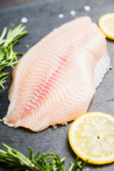 Raw tilapia fish fillet on the cutting board. Selective focus. Shallow depth of field.