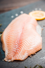 Raw tilapia fish fillet on the cutting board. Selective focus. Shallow depth of field.