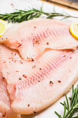 Raw tilapia fish fillet on the cutting board. Selective focus. Shallow depth of field.