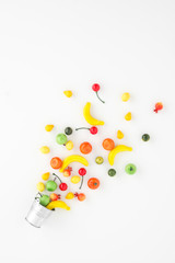 A scattering of many small different fruits on a white background. Mini copy of a metal bucket. The concept of diversity of flavors and additives. Multifruit.