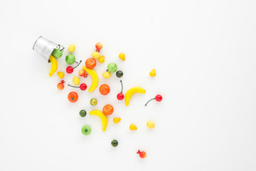 A scattering of many small different fruits on a white background. Mini copy of a metal bucket. The concept of diversity of flavors and additives. Multifruit.