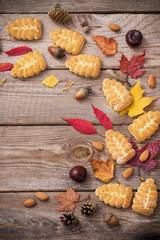 cookies and autumn leaves on  wooden background