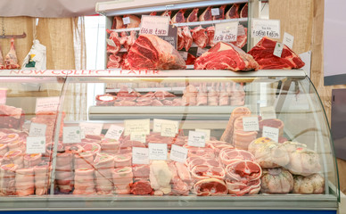 Variety of raw meat in chiller display at Butcher shop.