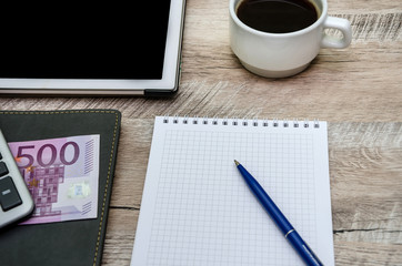 notebook, pen, cup of coffee and money on wooden background