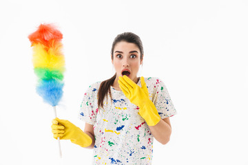 Photo of brunette woman 20s wearing yellow rubber gloves holding colorful duster while cleaning room