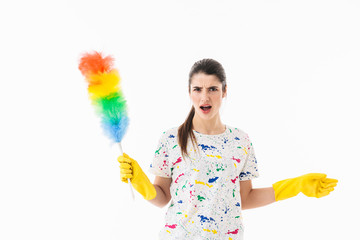 Photo of displeased housewife 20s wearing yellow rubber gloves holding colorful duster while cleaning room