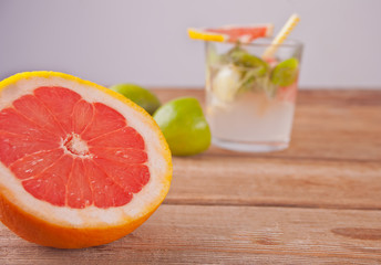 Cold juice with pink grapefruit, lime and mint leaves on wooden table