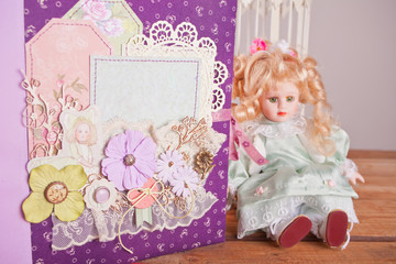 Scrapbooking album for baby in chebbi chic style and vintage doll on the wooden table