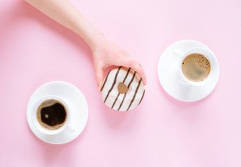 A child's hand takes a tasty donut; two cups of coffee