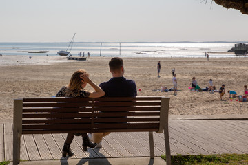 Couple sitting on a bench in summer sea background