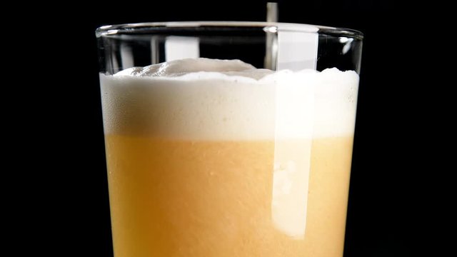 Cerveza cayendo en vaso sobre fondo negro 4k