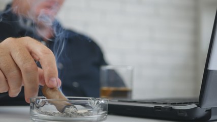 Obraz na płótnie Canvas Businessman Blurred Image Drinking Whisky Smoking Cigar and Working on Laptop