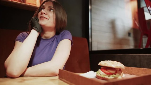Hungry girl eating hamburger on food court. Woman biting cheeseburger at fast food restaurant