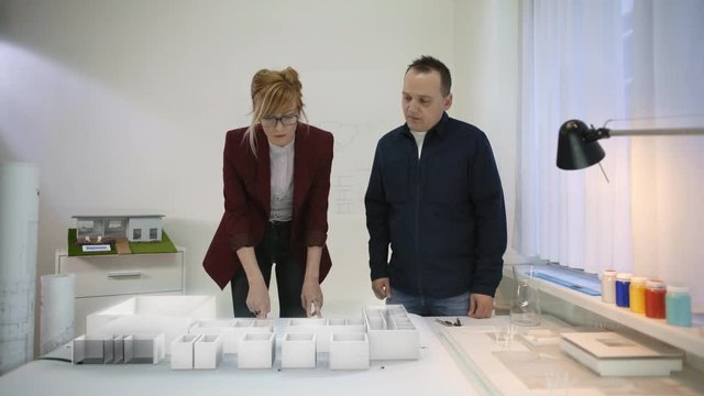 Two architects looking at a blueprint of a house, projecting augmented reality buildings on it