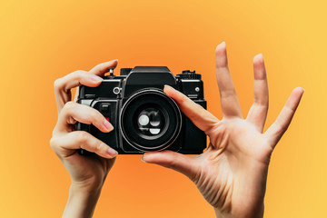 Vintage Camera in female hand. A photo. Photographer. Manual focus. Colored background. orange - 261031814