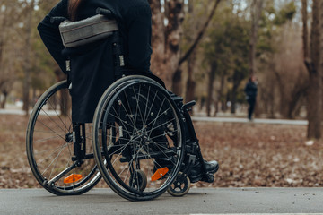 Close-up of male hand on wheel of wheelchair during walk in park