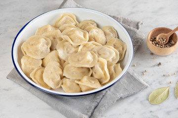 Homemade traditional Russian dumplings on a plate. Marble background, top view