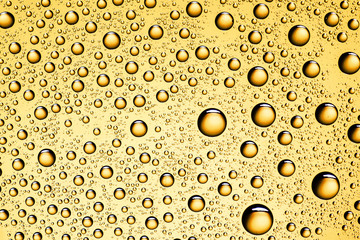 Water drops on yellow glass surface texture.