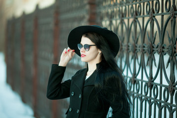 Fototapeta premium Young woman posing in black coat and black hat.