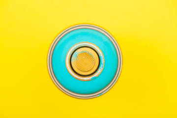 cyan colored spray can on yellow background 
