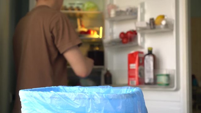The man in the kitchen. Household waste of fresh fruit and vegetables in the garbage bin. Food spoilage and loss. Fridge Organization