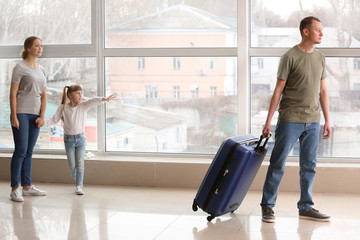 Man with suitcase leaving his family