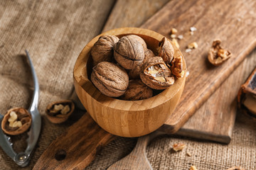 Bowl with tasty walnuts on table