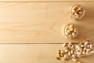 Jars with different tasty nuts on wooden table