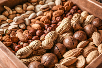 Box with different tasty nuts, closeup