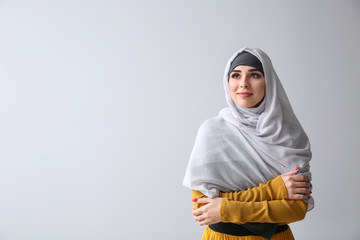 Beautiful Muslim woman on light background