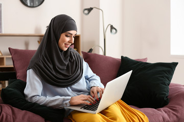 Muslim woman working on laptop at home