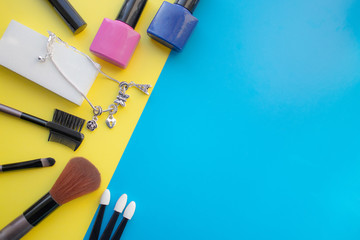 Cosmetic accessories. Brush for blush, brush, varnish on a yellow, blue background.