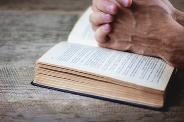 praying hands over a holy bible