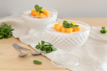 Bowls of delicious panna cotta on wooden table
