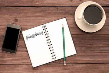 Business planning written on an open notebook, smartphone, Cup of coffee on a wooden table background. business, Finance.