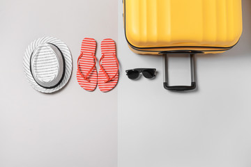 Suitcase, hat, flip-flops and sunglasses on light background. Travel concept