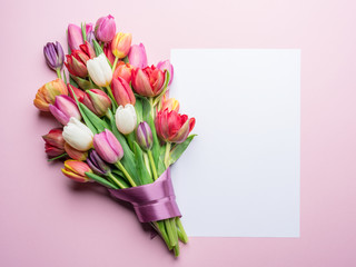 Bouquet of tulips and white paper on white background.