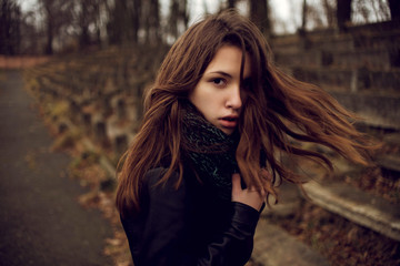 Sensual portrait shot of beautiful young girl walking in the old abandoned stadium on cold autumn day.