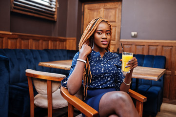 Portrait of beautiful young african business woman, wear on blue blouse and skirt, sitting with juice in cafe.