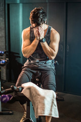 Fototapeta na wymiar Muscular young man drying sweat from his face with hands after cycling workout in a gym