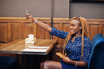Portrait of beautiful young african business woman, wear on blue blouse and skirt, sitting at...