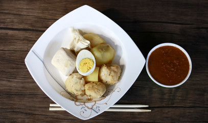 Siomay (fish cake dumplings) and peanut sauce on wood background. 